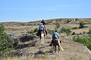 Guests riding their horses along a ridge in the eastern Montana badlands